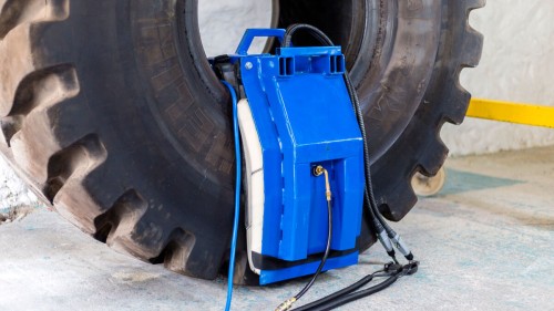 Boczne ujęcie systemu Monaflex do naprawy opon na gorąco (OTR Sidewall System), pokazujące elastyczne dopasowanie poduszek do opony oraz podłączone przewody grzewcze i pneumatyczne