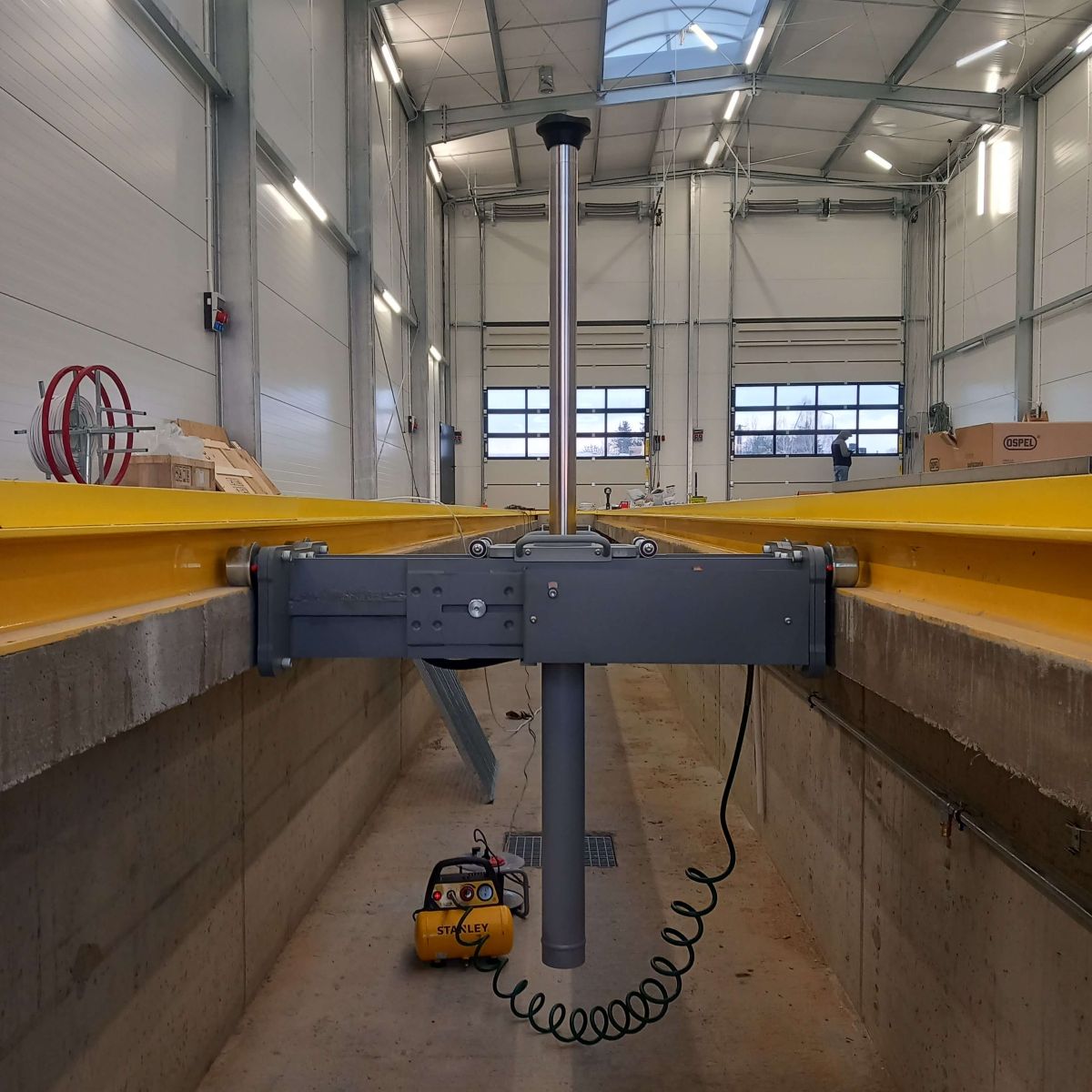 Pneumatyczno-hydrauliczny podnośnik kanałowy SNIT SG15 zamontowany na prowadnicach w kanale warsztatowy