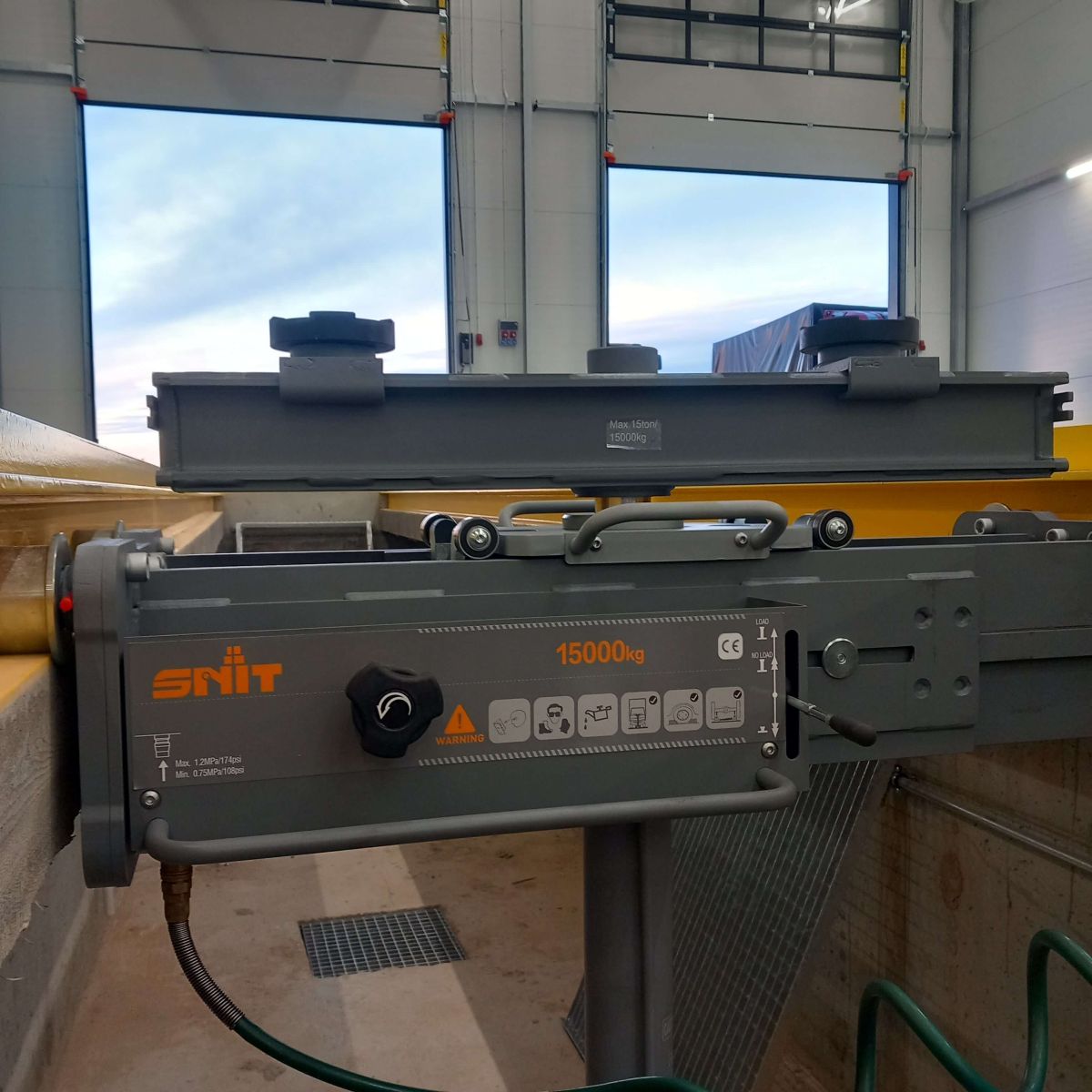 Podnośnik kanałowy SNIT SG15 wyposażony w trawers (belkę podpierającą) do bezpiecznego unoszenia osi pojazdów ciężarowych